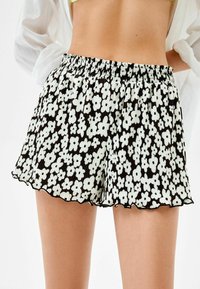 Černo-bílé květinové šortky s elastickým pasem, měkkou látkou, sklady, vroubkovaným lemem a odvážným květinovým vzorem.