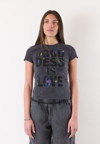 Camiseta gráfica negra de manga corta, con salpicaduras multicolores y un gran texto que dice "DIOSES ES AMOR". Tela suave, diseño ajustado.