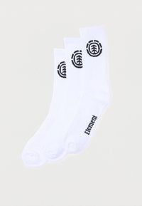 Trois paires de chaussettes blanches montantes empilées avec un léger chevauchement, chacune avec un logo d'arbre circulaire noir près du haut et le texte « Element » près des orteils.