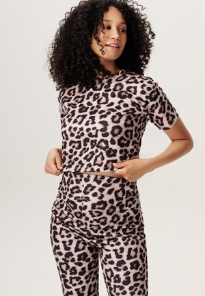 Luipaardprint sportoutfit bestaande uit een korte mouw top en leggings. Het materiaal is soepel met een lichte glans. Voornamelijk lichtroze met zwarte vlekken.