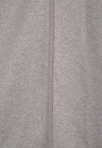 Ljust grått stickat tyg med en slät textur har en central söm och kontrasterande stygn, vilket visar noggrannhet i konstruktionen.