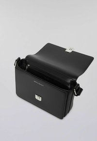 Borsa a mano in pelle nera con forma rettangolare, accessori in argento e chiusura a pattina. Presenta una tasca interna con zip e una tracolla regolabile.