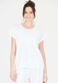 Valkoinen puuvillainen t-paita, jossa on pyöreä kaula-aukko ja lyhyet hihat, rento istuvuus ja sileä pinta. Yksinkertainen malli, ilman kuoseja tai koristeita.