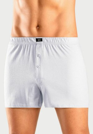 Männlicher Oberkörper, der schlichte weiße Baumwollboxershorts mit einer zwei-Knopf-Knopfleiste und einem elastischen Bund trägt, der mit H.I.S. beschriftet ist.