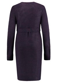 Stickad klänning i mörklila med långa ärmar, ribbade muddar och midjebälte. Strukturerad tyg med ett enhetligt mönster genomgående.