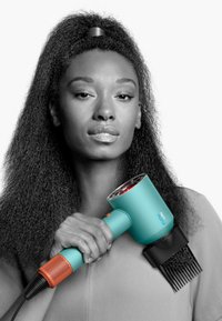 Turquoise haardroger met zwarte accessoires, voorzien van een oranjekleurig handvat. Het handvat is afgerond, met een transparante voorkant die rode lampjes toont.