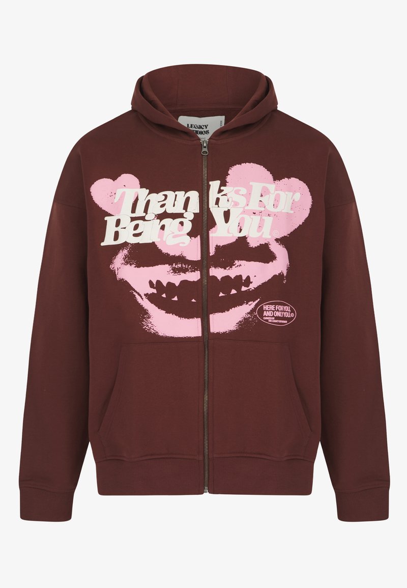 Μακρυμάνικο φούτερ καφέ-κόκκινου χρώματος με φερμουάρ, κατασκευασμένο από απαλό ύφασμα, με μεγάλο λευκό και ροζ γραφικό σχέδιο και κείμενο. Διαθέτει μπροστινές τσέπες και κουκούλα με κορδόνι.