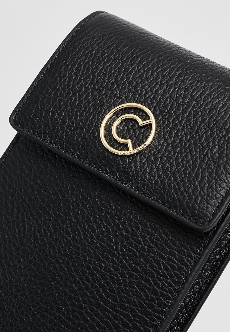 Schwarzes Lederetui mit strukturiertem Finish, ausgestattet mit einem goldenen, runden Logo auf dem Deckel. Kompaktes Design mit einem sanften Verschlussmechanismus.