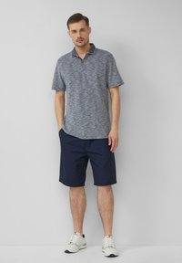 Męska koszulka polo z krótkim rękawem w mieszankowym szarym-niebieskim materiale; ciemnoniebieskie szorty; jasne sneakersy; stojący na neutralnym tle.