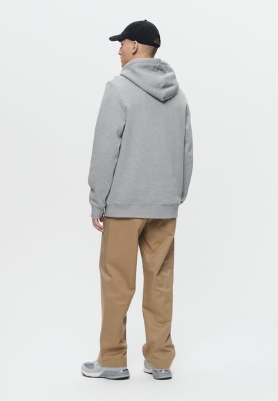 Gray hooded sweatshirt, elastic hem and cuffs, paired with tan wide-leg pants and gray sneakers. Black cap completes the look.