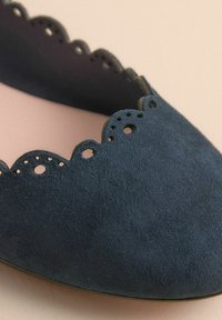 Navyblaue Ballettschuhe aus Wildleder mit gewelltem Rand und kleinen Perforationen. Glatte Textur, runde Zehenform.