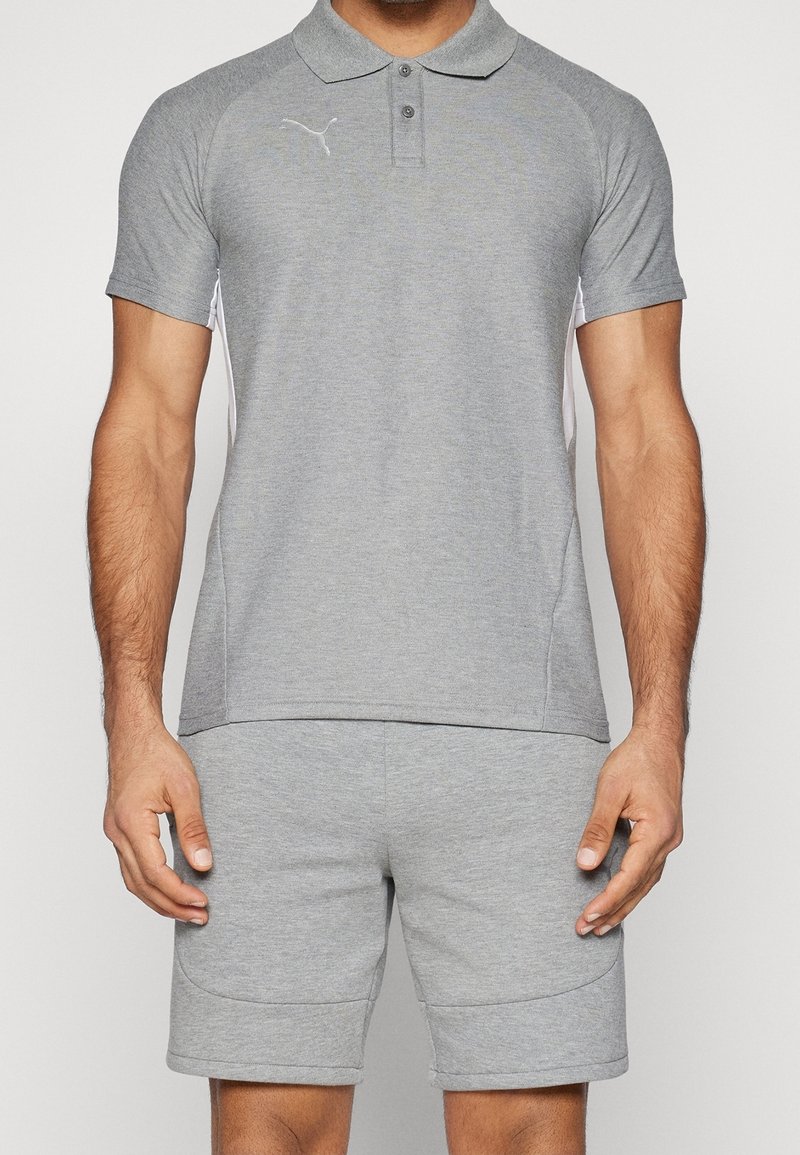 Polo gris en tissu doux avec manches courtes, col boutonné et accents latéraux blancs. Associé à un short gris assorti.