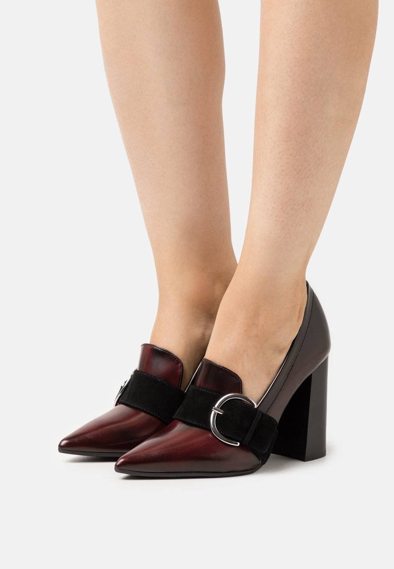 Chaussures à talons hauts à bout pointu en cuir bordeaux et noir à finition mate, dotées d'une large bride avec boucle en métal, et d'un talon épais.