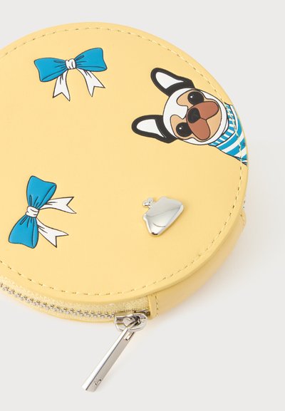 Porte-monnaie rond jaune avec fermeture éclair, décoré de nœuds bleus et d’un chien portant une chemise rayée, et un petit charme argenté pour porte-monnaie.