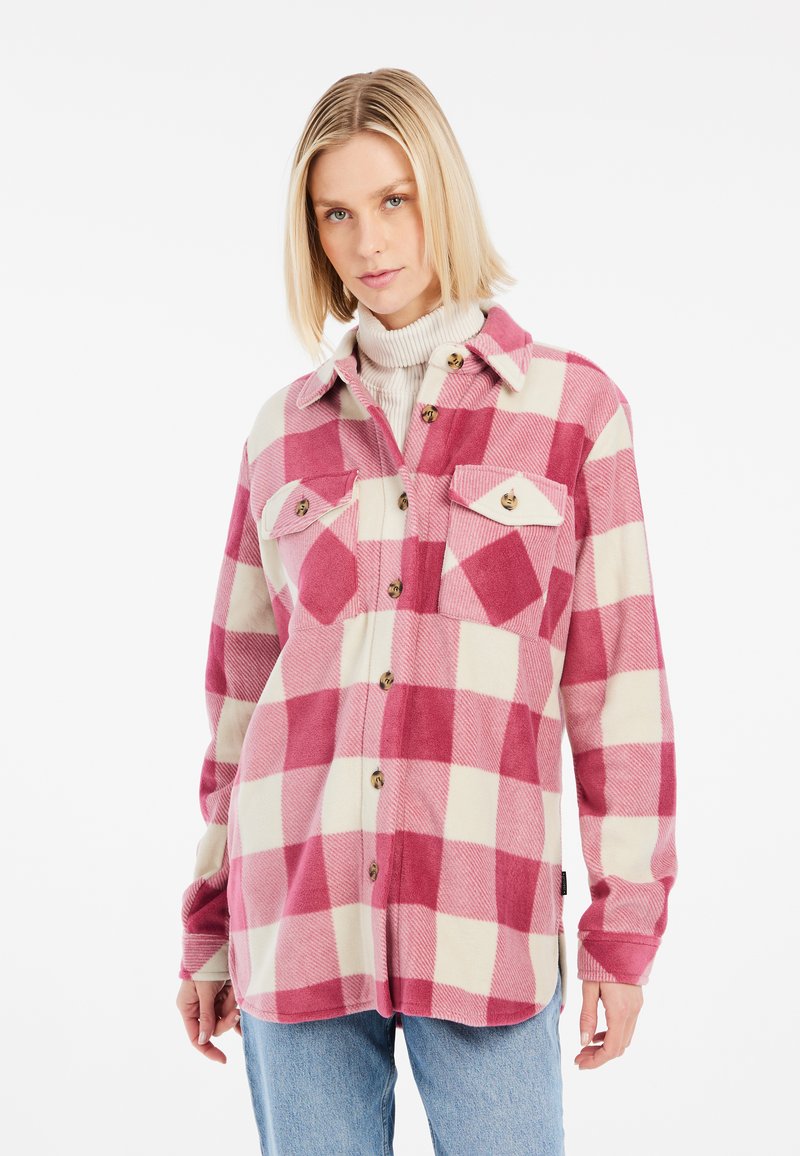 Chemise en flanelle à carreaux rose et crème, avec un devant à boutons, deux poches poitrine et une texture douce. Manches longues et ourlet arrondi.