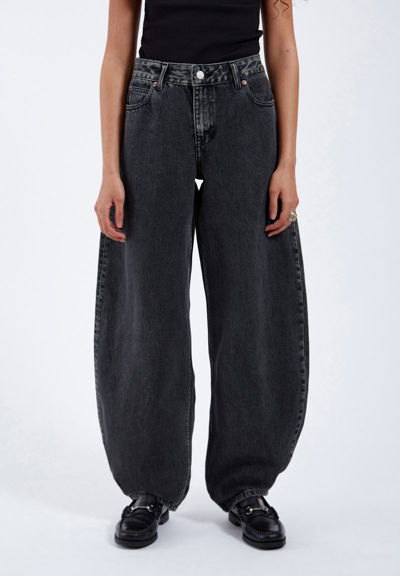 Mörkgrå överdimensionerade denimjeans med hög midja, femfickorsdesign och knappstängning. Slät textur med subtila blekta detaljer.