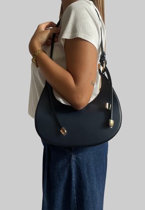 Borsa a tracolla in pelle nera con forma curva, caratterizzata da dettagli in oro e due manici. Texture liscia con design minimalista.