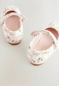 Scarpine da ballet con motivo floreale in rosa tenue, dotate di cinturino e hardware in oro rosa. Punta rotonda con una parte superiore in tessuto liscio e suola testurizzata.