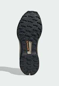 Svart gummisul med djupa, vinklade mönster. Har "Continental"-logotyp i orange och en texturerad mellansula för grepp.