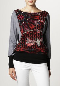 Haut à manches longues avec un motif floral noir orné d'accents rouges, bleus et blancs. Manches grises et bandeau côtelé noir à la taille.