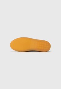 Sål med rund form, laget av gummi, i brun-oransje farge, med teksturert grep mønster og glatte kanter.