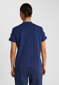 Mörkblå bomulls t-shirt med rund halsringning och korta ärmar, med vita detaljer på axlarna och en avslappnad passform.