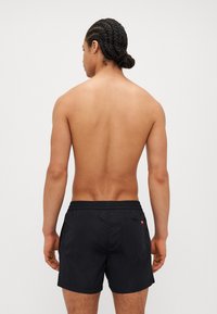 Svart badebukser med snøring, elastisk liv, og baklommens detaljer. Glatt stoff, lengde til midten av låret, uformell design.