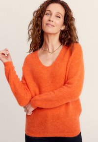 Helles Orange, weicher Strickpullover mit tiefem V-Ausschnitt und langen Ärmeln. Verfügt über einen lässigen Schnitt und eine leicht flauschige Textur.