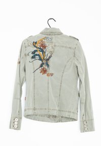 Giacca verde chiaro con ricamo floreale sul retro, caratterizzata da un design strutturato, polsini con bottoni e colletto classico.