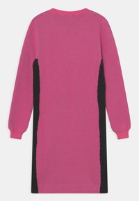 Abito in maglia rosa con pannelli laterali neri, maniche lunghe e scollatura rotonda. Texture morbida, con dettagli a contrasto.