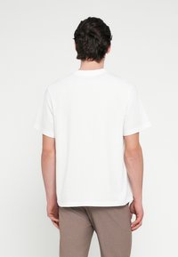 White cotton t-shirt with a classic crew neck and short sleeves, featuring a relaxed fit and a smooth texture. Simple, no patterns or accents.