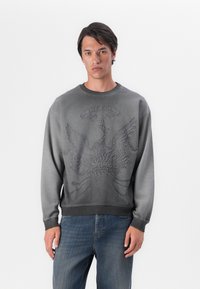 Grå bomulds sweatshirt med et tekstureret ørn grafik og logo på fronten. Lange ærmer og ribbede manchetter fuldender designet.