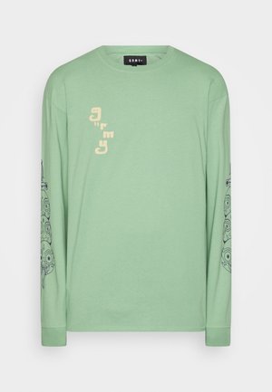 Vihreä pitkähihaisen puuvillan T-paita, jossa painettua tekstiä edessä ja yksityiskohtainen graafinen kuvio molemmissa hihoissa. Yksinkertainen pyöreä kaula-aukko ja hihansuut.