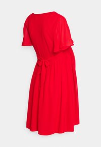 Vestido vermelho de mangas curtas em tecido leve, com um laço nas costas, saia fluida e decote redondo. Textura suave sem padrões.