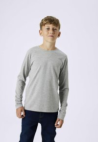 Langärmliges graues Baumwoll-T-Shirt mit rundem Ausschnitt, geradem Schnitt und weicher Textur, kombiniert mit blauen Jeans.