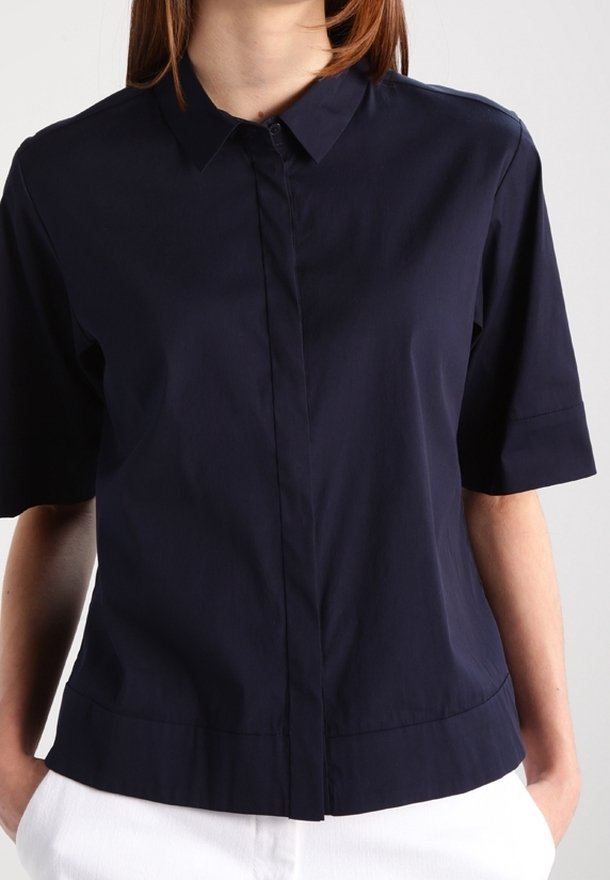 Marinblå kortärmad skjorta med krage, knappstängning och rak nederkant. Tillverkad av ett glansigt, lätt tyg.