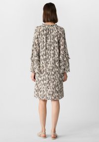 Sukienka z krótkim rękawem w jasny wzór imitujący skórę węża, z falbankami na rękawach i luźnym krojem, okrągłym dekoltem i długością do kolan.