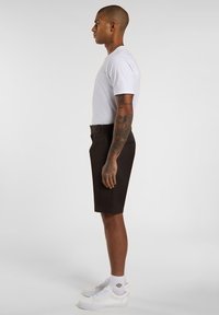 White crew neck t-shirt, black shorts, and white sneakers. The shorts are tailored with a smooth texture and feature a back pocket.