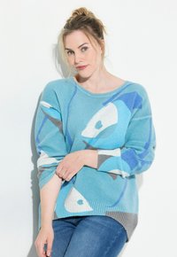 Ljusblå tröja med abstrakta mönster i vitt, grått och mörkblått. Har en lös passform och ribbade ärmslut. Mjuk textur.