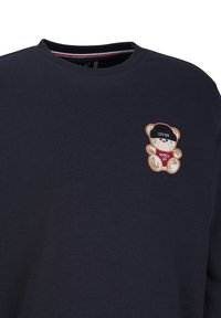 Marineblauwe sweatshirt met een ronde halslijn, voorzien van een geborduurd bruin teddybeertje ontwerp op de borst en tekst "APRES SKI."