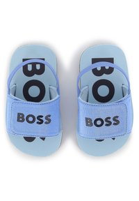 Vaaleansiniset liukusandaalit, joissa on teksturoitu yläremmi ja logo. Pohjassa on suuri musta "BOSS" -teksti, joka tarjoaa kontrastia.