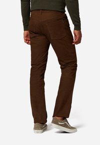 Bruine katoenmix pantalons met een aansluitend design, achterzakken en een subtiele textuur. Gecombineerd met grijze sneakers voor een casual look.