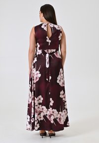 Langes, dunkeldunkles bordeauxfarbenes Kleid mit Blumenmuster, Schlüssel-Loch-Ausschnitt auf der Rückseite, Taillengurt und einem fließenden Rock. Glattes Gewebe mit dezentem Glanz.