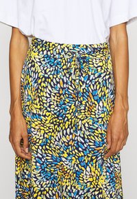 Falda con patrón floral que presenta colores vibrantes en azul, amarillo y blanco, hecha de una tela ligera con talle atado y un corte relajado.