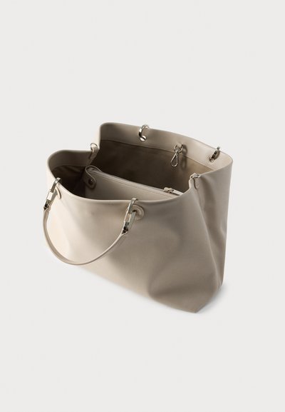 Μπεζ τσάντα tote από λείο συνθετικό υλικό, ανοιχτό πάνω μέρος, ασημένια μεταλλικά μέρη και διπλές λαβές. Διαθέτει εσωτερική τσέπη με φερμουάρ για οργάνωση.