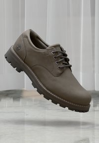 Braune Leder-Schuhe mit glatter Oberfläche, runder Zehenform, Schnürdesign und strapazierfähiger Gummisohle mit ausgeprägtem Profil. Timberland-Logo sichtbar.