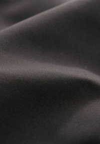 Tumma harmaa kangas, jolla on sileä tekstuuri, hienostunut kiilto ja hienot kudontakuviot, luoden pehmeän ja virtaavan ilmeen.