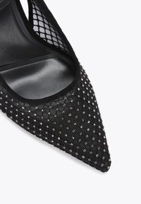 Escarpin noir à bout pointu avec des accents en maille et orné de petits sequins argentés. Intérieur en cuir lisse et extérieur texturé.