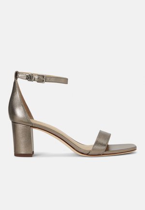 Sandale à talons hauts argent métallique avec une bride de cheville, bout carré et talon chunky. Texture lisse et design minimaliste avec boucle ajustable.