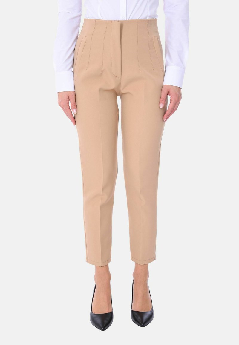 Pantaloni beige su misura con vita alta, fronte piatto e pieghe. Abbinati a tacchi a punta neri, presentano un tessuto morbido e leggero.